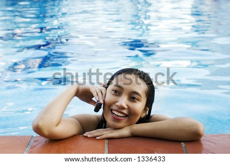 Asian woman making a phone call at swimming pool