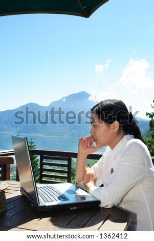 Asian woman working at a restaurant with a mountain in the background.