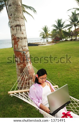 Asian woman working on her vacation at the beach