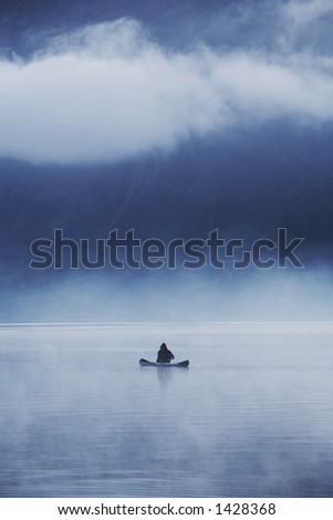 Fisherman with his small boat in a misty morning