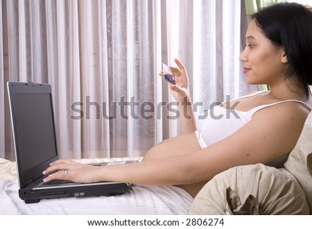 Pregnant woman holding a credit card surfing the net