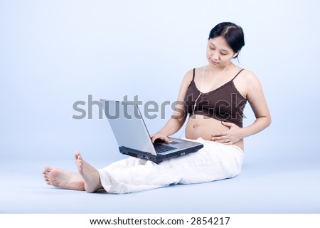 Isolated pregnant businesswoman working on laptop shot over blue bakcground