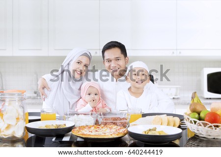 Portrait of happy family smiling together in the kitchen while sitting in front of dining table