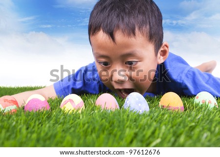 Easter egg hunt. Cute boy find easter eggs hidden in fresh green grass.