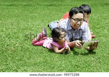 Happy Family: Father playing with a digital tablet. Shot outdoor on a sunny summer day