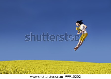 Beautiful asian woman jumping on the canola field with flower