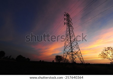 Silhouette Electric transmission tower with power line with the orange cloud and blue sky.