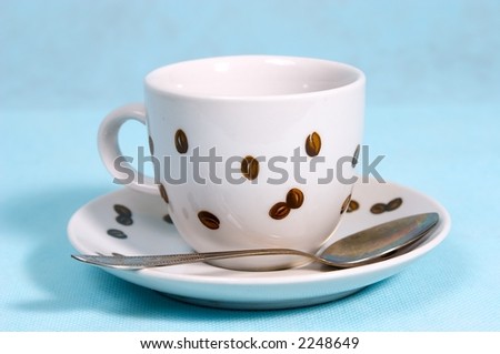 Coffee cup on saucer on a blue background. On a cup coffee grains are drawn.