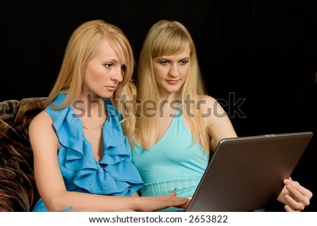 Two beautiful women work on notebook Black background.
