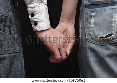 Hand in hand. Man and woman. Closeup of hands against black background.