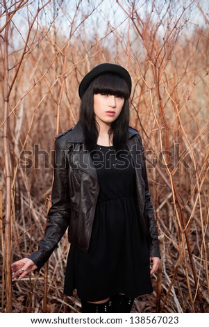 Beautiful female in black dress and hat posing on the nature