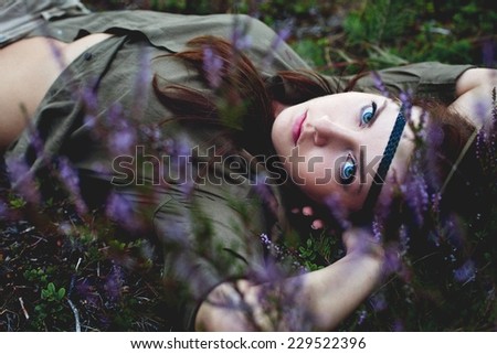 A beautiful blue eyed woman laying down among purple heather
