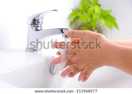 washing hands under flowing tap water in the bathroom