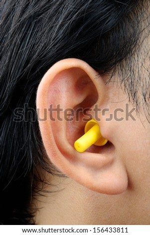 closeup yellow ear plug isolated into the ear