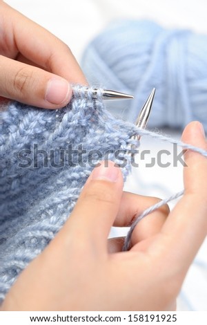 Woman knitting with purple wool.