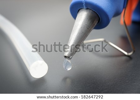 closeup hot glue gun nozzle with melted glue dripping out