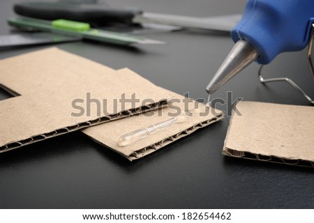 closeup hot glue gun apply the glue to corrugated cardboard