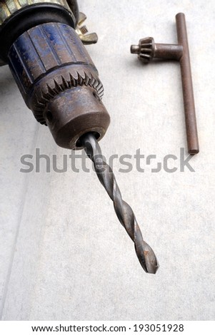 metal drill chuck with a spiral drill bit attached to it