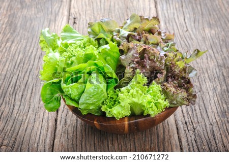 closeup isolate fresh lettuces in wooden bowl on wooden desk