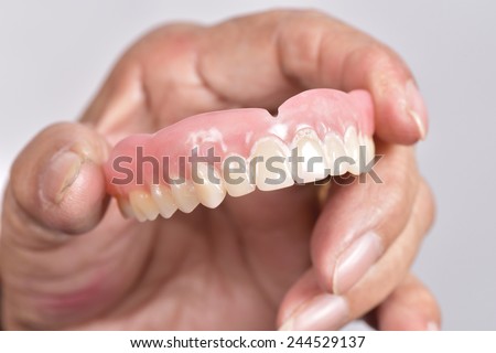 false tooth in senior woman\'s hand