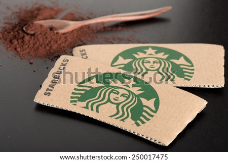 BANGKOK, THAILAND - FEBRUARY 04, 2015: Starbucks coffee cup sleeve and cocoa powder on black board. Starbucks is the world\'s largest coffee house with over 20,000 stores in 61 countries.