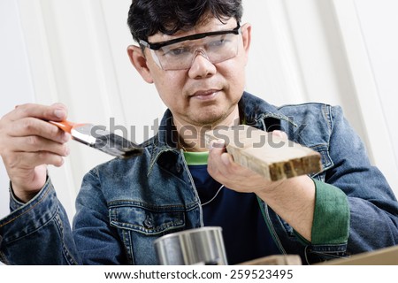 asia man using paintbrush painting wooden plank