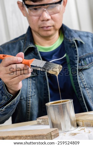 asia man using paintbrush painting wooden plank