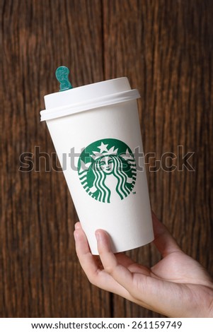 BANGKOK, THAILAND - MARCH 17, 2015: White paper cup with Starbucks logo in hand. Starbucks is the world\'s largest coffee house with over 20,000 stores in 61 countries.