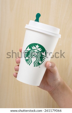BANGKOK, THAILAND - MARCH 17, 2015: White paper cup with Starbucks logo in hand. Starbucks is the world\'s largest coffee house with over 20,000 stores in 61 countries.