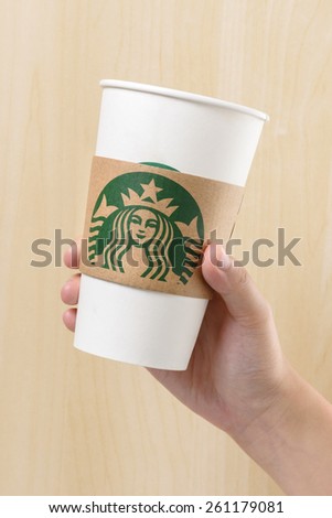 BANGKOK, THAILAND - MARCH 17, 2015: White paper cup with Starbucks logo in hand. Starbucks is the world's largest coffee house with over 20,000 stores in 61 countries.