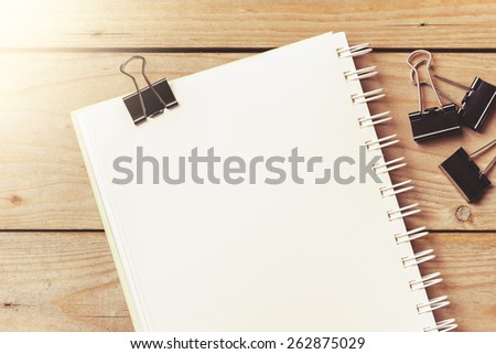 black binder clips and notebook on wooden plank
