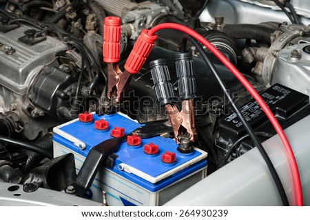 car battery with jumper cable in engine room