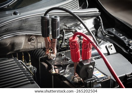 car battery with jumper cable in engine room