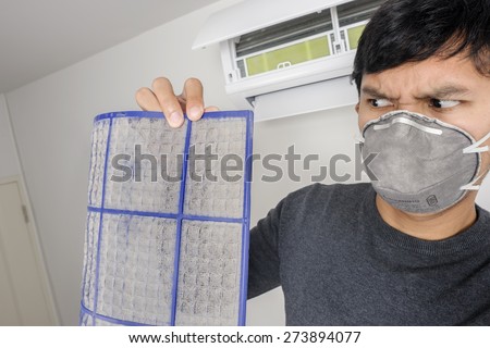 a man with mask showing dirty air filter before cleaning