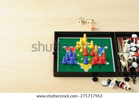 BANGKOK, THAILAND - MAY 07, 2015: Playing mini Chinese checkers in multi games in one box on wooden desk with space for adding text.