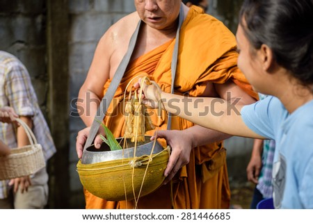 CHONBURI, THAILAND - OCTOBER 09, 2014: Unidentified people offer food to monks in Tak Bat Devo. Tak Bat Devo is the tradition to recall when the Buddha returned from his visit to his mother in Heaven.