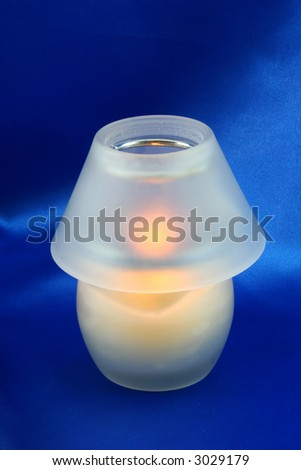 white, candle jar lightening on a blue satin background