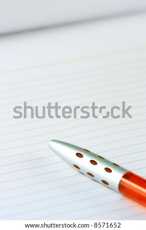 close-up of a red pen on a notebook with lines