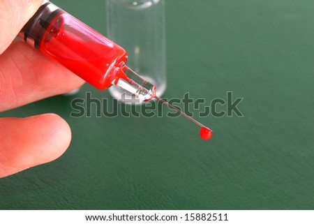 syringe needle and medical stuff on green surface with blood drops on it