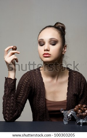 Luxury chocolate, stunning young brunette woman with bonbons.