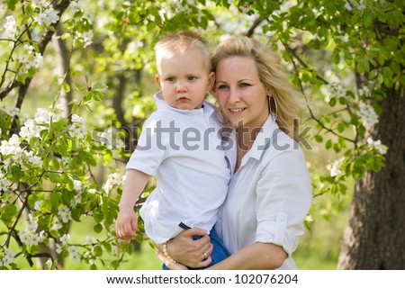 Portrait of an attractive mom and her son outdoors in the garden at spring.