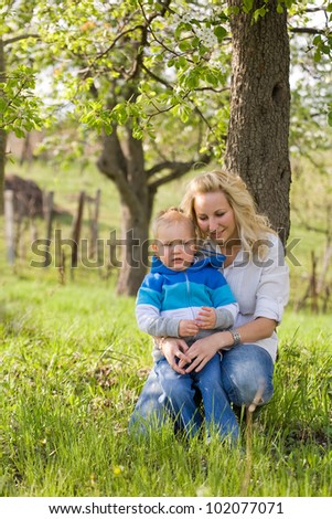Portrait of an attractive mom and her son outdoors in the garden at spring.