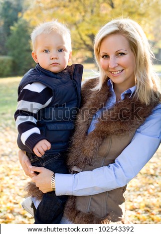 Portrait of cute kid and pretty mom having fun outdoors at fall.