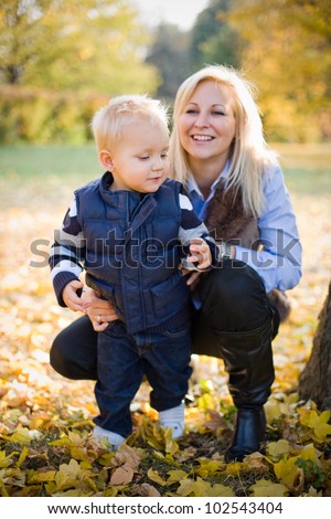 Portrait of cute kid and pretty mom having fun outdoors at fall.