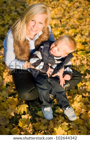 Having fun with mom, beautiful young mtoher with her son outdoors in the park at fall.