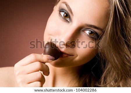 Sensual chocolate fun, young brunette beauty tasting chocolate.