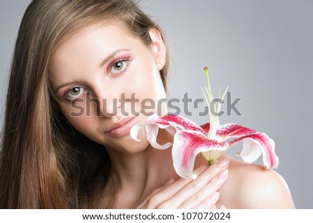 Beauty shot of young brunette woman with colorful flower and makeup.