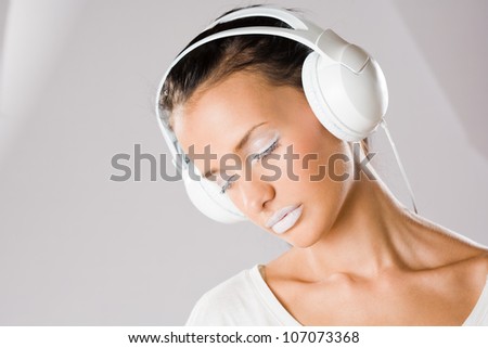 Dreamy young music lover, beautiful young brunette wearing big white headphones.