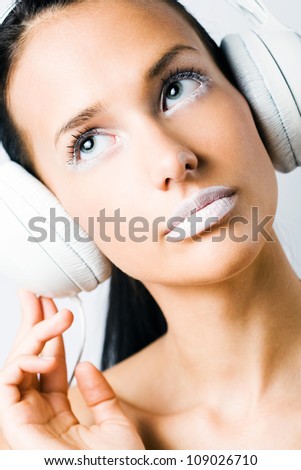 White noise, young brunette listening to music in white headphones, creative makeup.