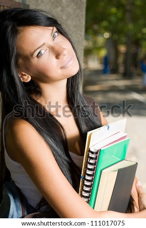Portrait of a tanned student beauty outdoors in the park with her exercise books.